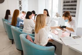 Group of girlfriends relax on manicure procedure in beauty salon. (Adobe)