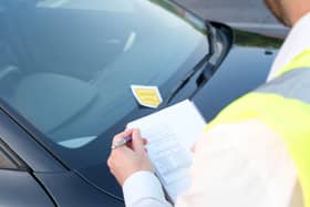 A traffic warden gives a ticket fine for a parking violation