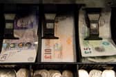 An open cash register containing pound coins and notes is pictured in a convenience store in London