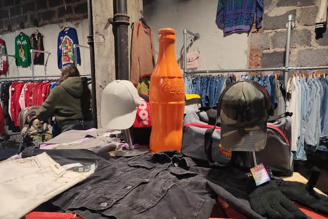 Top notch visual merchandising includes a large orange Coca Cola bottle surrounded by an array of caps and jackets | Image Ria Ghei