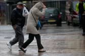 People walk in rain and high winds.
