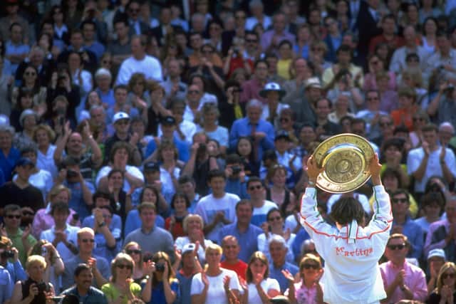5 Jul 1997: Martina Hingis of Switzerland holds the trophy aloft to show the spectators after her victory in the Women's Singles final against Jana Novotna of the Czech Republic during the Lawn Tennis Championships at Wimbledon in London. (Credit: Clive Brunskill/Allsport for Getty Images)
