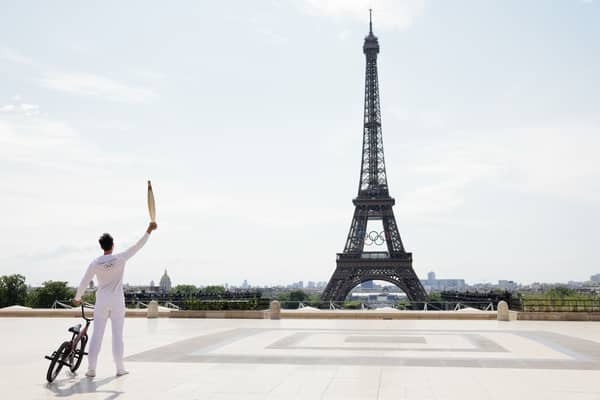 Torch bearer Matthias Dandois, French bicycle rider, poses for a photo with the Olympic Torch with the Eiffel Tower in view (Photo: Maja Hitij/Getty Images)