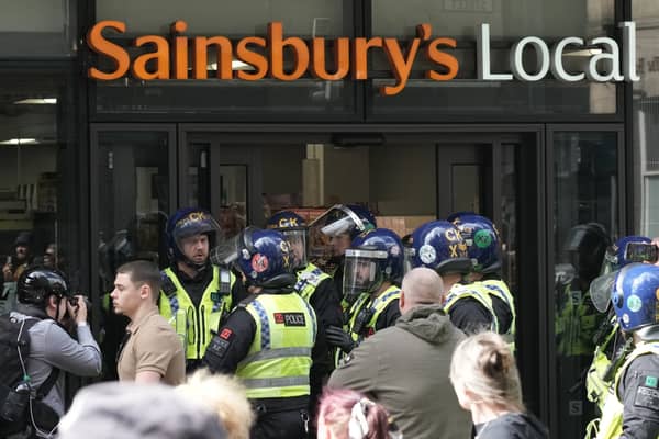 Police gather outside the Sainsbury’s local that was targeted by looters. 