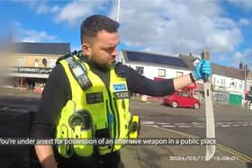 Police officer pulls huge machete from dealer's coat.
