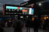 Rail travellers look at an electronic information board displaying train time information outside Euston Station in London. Photo: JUSTIN TALLIS/AFP via Getty Images
