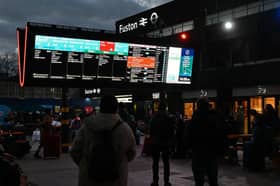 Rail travellers look at an electronic information board displaying train time information outside Euston Station in London. Photo: JUSTIN TALLIS/AFP via Getty Images