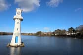 A white clock tower surrounded by water in a serene location