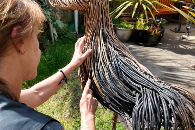 Artist Helena weaves a dog sculpture out of willow twigs.