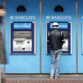 A man uses a cashpoint machine at a Barclays Bank 