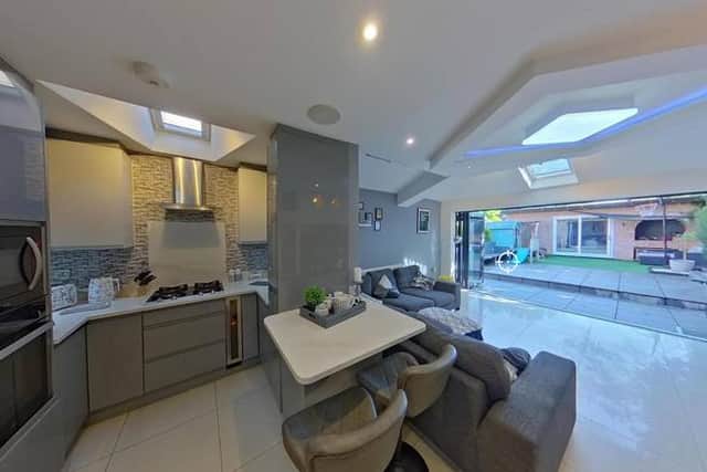 The contemporary kitchen and dining space features sleek grey units, integrated appliances and bifold doors opening onto the garden