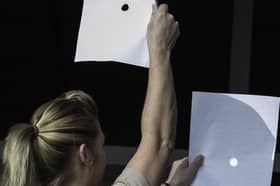A woman uses two sheets of paper as the Sun is obscured by the Moon during a partial solar eclipse at Skegness seafront in Lincolnshire, north England on 20 March 2015.