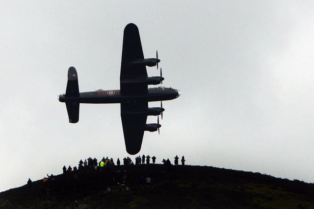 Spectators on a hill look on as a Lancaster bomber flies over Ladybower reservoir in the Derbyshire Peak District to mark the 65th anniversary of the World War II Dambusters mission on May 16, 2007 in Derwent. Ladybower and Derwent reservoirs were used by the RAF's 617 Squadron in 1943 to test Sir Barnes Wallis'  bouncing bomb before their mission to destroy dams in Germany's Ruhr Valley.  (Photo by Christopher Furlong/Getty Images)