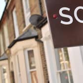 An estate agent's "sold" board stands outside a residential building.