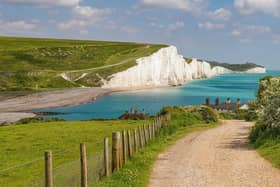 The White Cliffs of Dover are on the horizon, there is a country lane leading down to the sea.