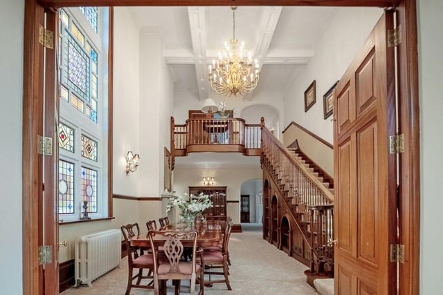 Original stained glass windows are a feature of this superb dining room which has an impressive staircase rising to the first floor.